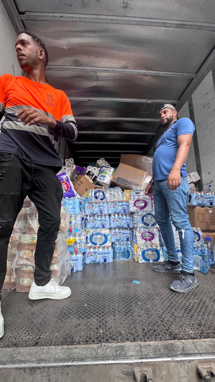 Two people inside a truck carrying bottled water, boxes and hygiene supplies