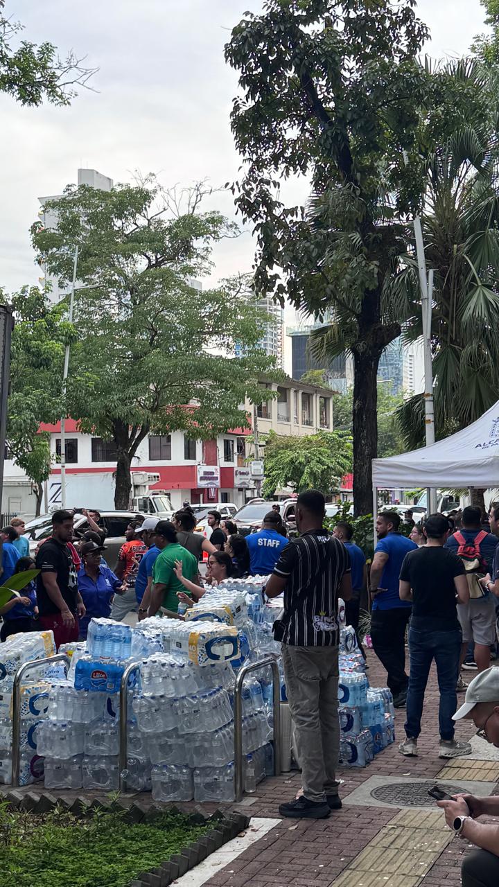 People working around stacks of donated bottled water at an outdoor collection point